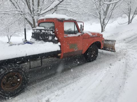 1961 Ford F-350 - This orange truck, likely a 1957 model, is equipped with a snow plow and is seen in a snowy environment.