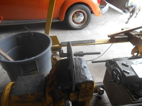 1992 Ford Bronco - A metal part is secured in a vise, with an orange vehicle and a dog in the background.