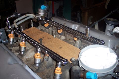 1995 Ford Bronco - Close-up view of engine fuel injectors and fuel rails, with a piece of cardboard placed over part of the engine.