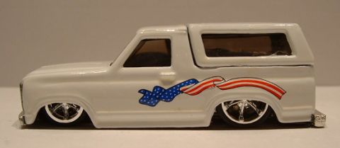 1979 Ford Bronco - A white die-cast Ford Bronco casting slammed to the ground in a full side profile, wearing polished multi-spoke chrome wheels with low-prof…