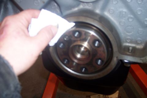 1995 Ford Bronco - A hand wipes down a metal engine part, likely preparing it for reassembly or inspection.