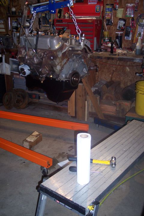 1995 Ford Bronco - An engine is suspended by a chain hoist, ready for installation or removal in a workshop setting.