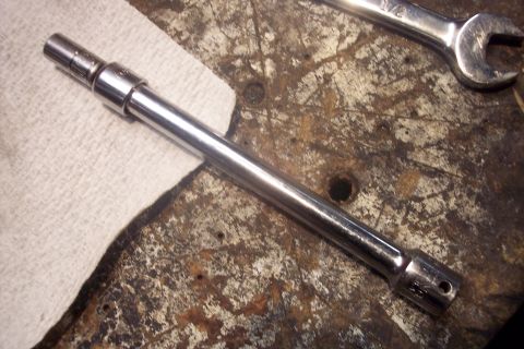 1995 Ford Bronco - A chrome socket extension and a 1/2 inch wrench are shown on a worn wooden workbench.