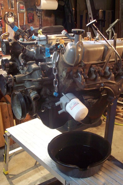 1995 Ford Bronco - Engine assembly with oil filter attached, resting on a stand over a drain pan.