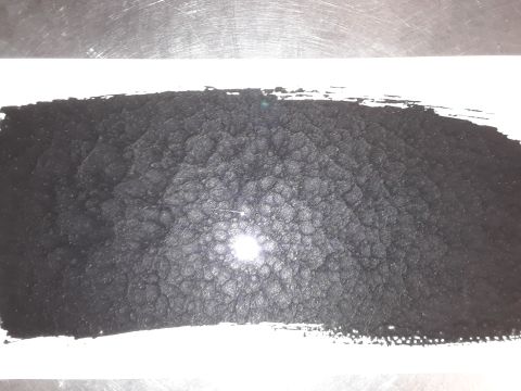 1985 Ford Bronco - A pile of black granular material is shown, possibly engine parts or debris, on a white surface.