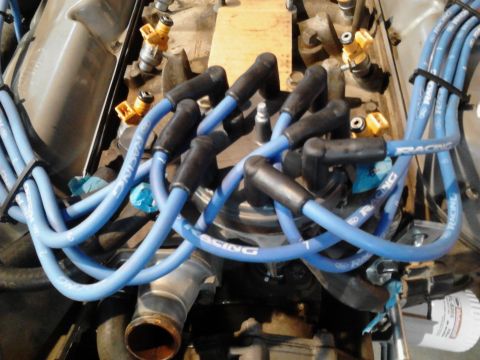 1995 Ford Bronco - Close-up of blue spark plug wires on an engine, with visible text on the wires.