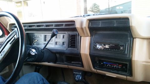 1985 Ford Bronco - The interior dashboard of a 1985 Ford Bronco shows the steering wheel, instrument cluster, and two aftermarket stereo units.