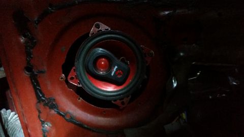 1985 Ford Bronco - Speaker installation in progress, showing the speaker mounted to a red metal surface.