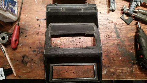 1985 Ford Bronco - Center console part for a vehicle, possibly for speaker installation, on a workbench with tools.