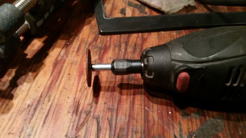1985 Ford Bronco - A rotary tool with a cutting disc is shown on a wooden workbench, with other tools in the background.