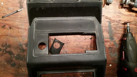 1985 Ford Bronco - Center console part, likely for a speaker install, with a Dremel tool nearby.
