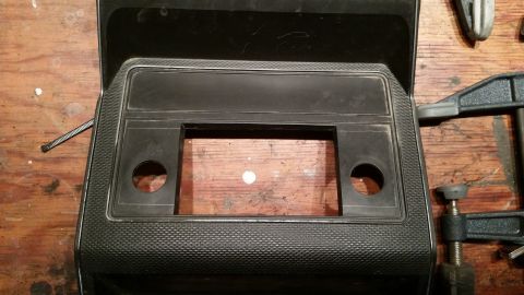 1985 Ford Bronco - Dashboard trim panel with radio cutout and speaker holes, held by clamps.