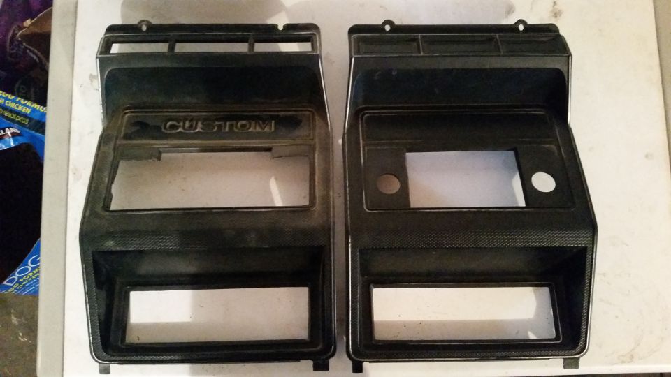 Two black plastic dashboard trim pieces, one labeled "CUSTOM", with cutouts for radio and gauges