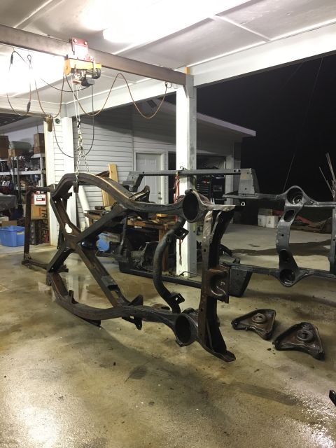 1962 Ford Galaxie - The bare frame of a car is suspended by a hoist, awaiting restoration or repair.