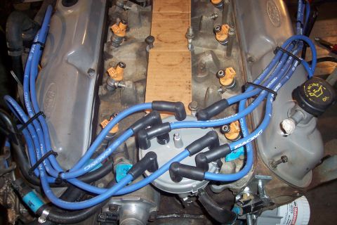 1995 Ford Bronco - Close-up view of an engine, blue spark plug wires and yellow fuel injectors, with a distributor cap in the center.