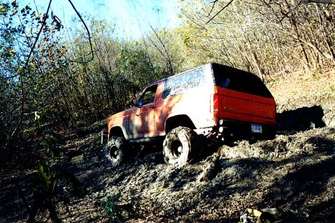 1984 Ford Bronco - This Ford Bronco is navigating a challenging muddy trail, its off-road capabilities.