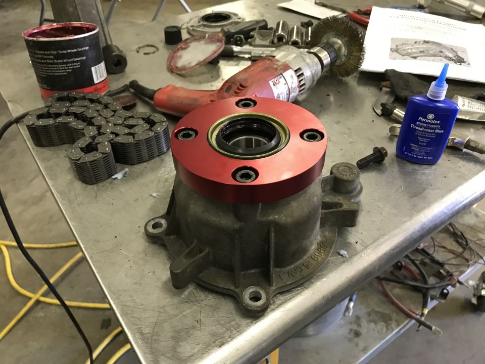 differential housing with red adapter, chains, grease, and tools on workbench