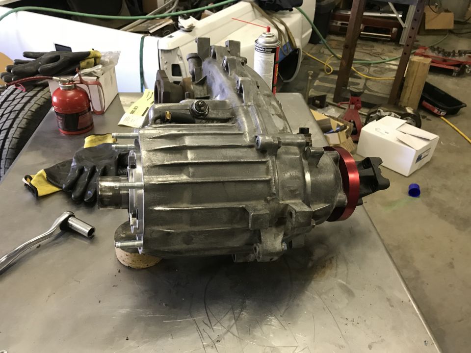 Transfer case on workbench with tools and gloves