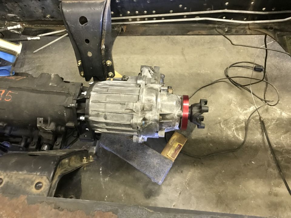 Transfer case and transmission assembly mounted on a stand, with visible wiring and brackets