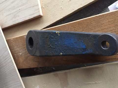 1967 Ford Custom Wagon - A close-up view of a dark metal automotive part with blue paint, placed on a wooden surface.