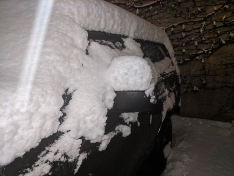 1995 Ford Bronco - A vehicle is heavily covered in snow, obscuring its make and model.