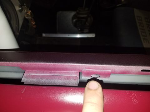 1968 Ford Bronco - Close-up of a car's door latch mechanism, with a finger indicating a specific point.