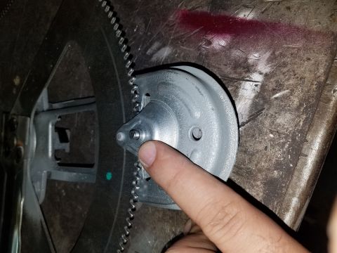 1968 Ford Bronco - A finger points to a component of a flywheel and starter gear assembly, likely for a vehicle.