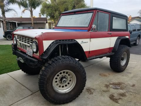 1968 Ford Bronco - A modified 1968 Ford Bronco is parked in a driveway with another vehicle in the background.
