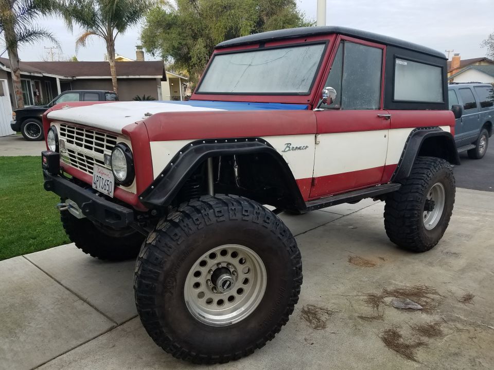 Red and white Ford Bronco with black top and large tires