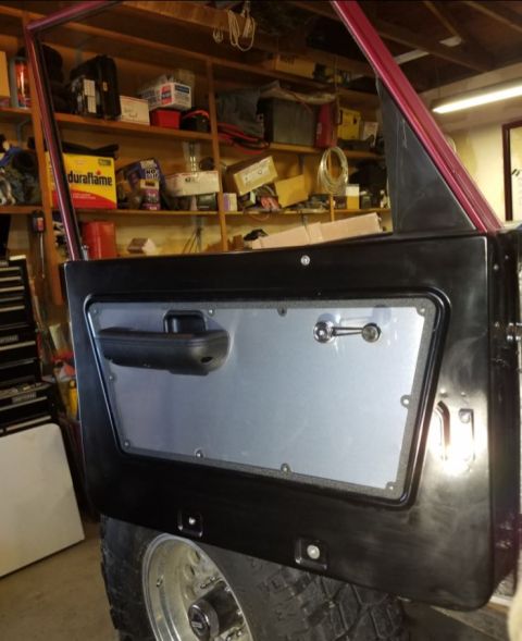 1968 Ford Bronco - The interior of a vehicle door is shown, with a focus on the panel, handle, and armrest.