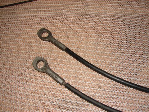 1973 Ford Ranchero - Two black cables with metal eyelet ends are shown against a textured surface.