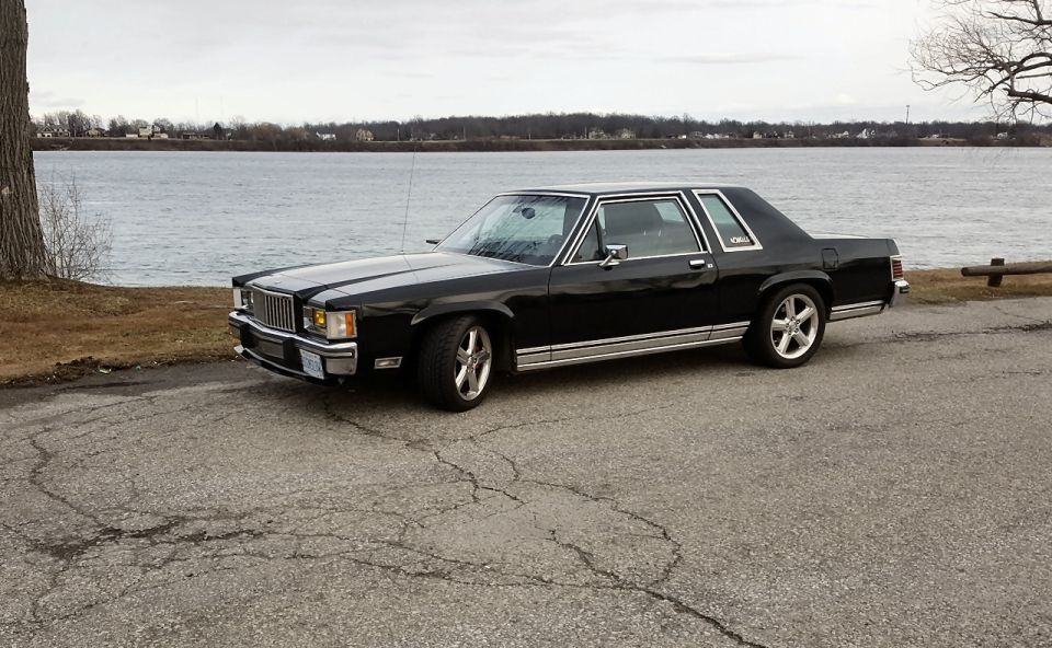 Black 1985 Mercury Grand Marquis parked near a body of water