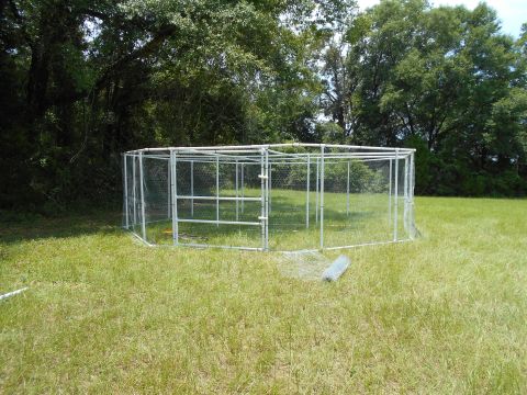 1992 Ford Bronco - An outdoor enclosure is shown in a grassy field, with trees in the background and a roll of wire mesh on the ground.
