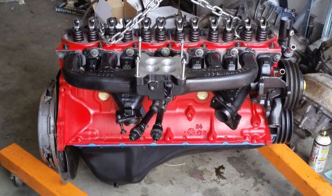 1981 Ford Bronco - A red V8 engine with a carburetor and chains is mounted on an engine stand, ready for installation or repair.