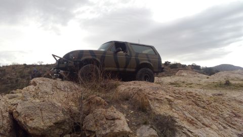 1996 Ford Bronco - This 1996 Ford Bronco navigates a challenging rocky incline under a cloudy sky.