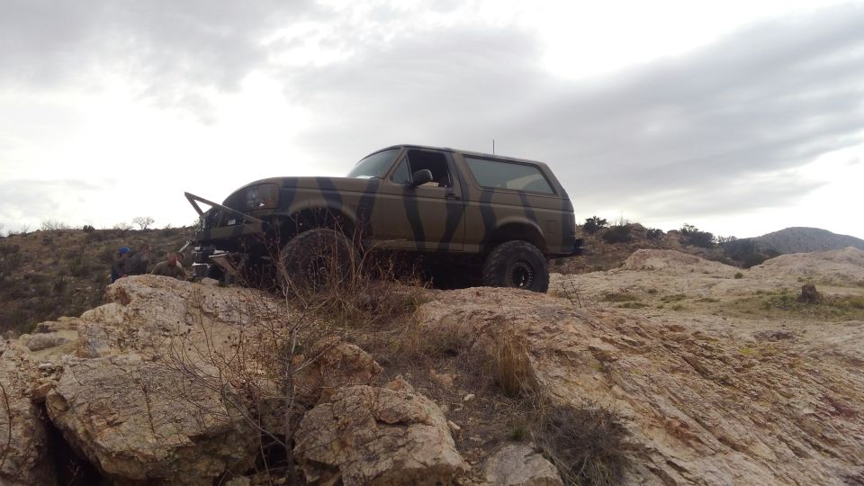 Camouflaged 1996 Ford Bronco on rocky hill, 3/4 front view