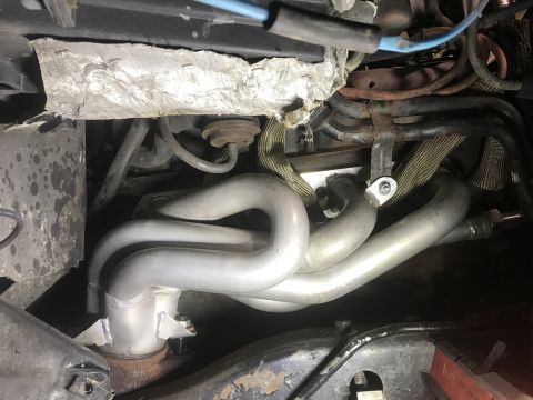 1995 Ford Bronco - The engine's exhaust manifold and associated wiring are visible in this close-up view.