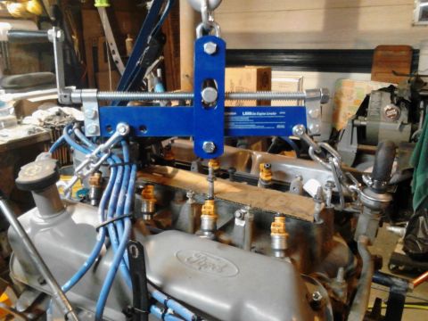 1995 Ford Bronco - A Ford V8 engine is suspended by a blue engine hoist, undergoing maintenance in a workshop.
