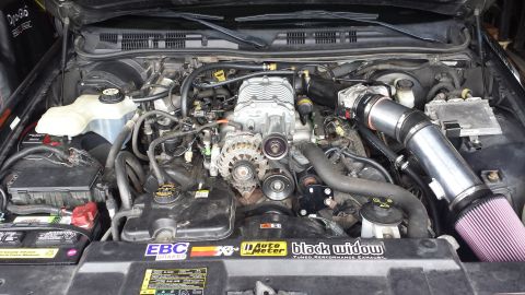 2005 Mercury Grand Marquis - The engine bay shows a supercharger and custom parts, with several performance brand stickers on the radiator cover.