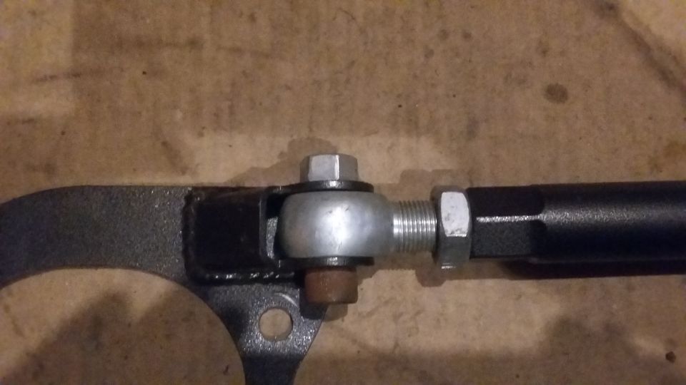 Close-up of an adjustable suspension rod with a ball joint and hex nuts