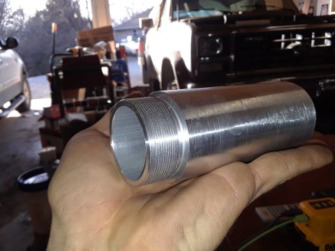 1994 Ford Bronco - A metal threaded part is held in a hand, with a black 1990s Ford Bronco visible in the background.