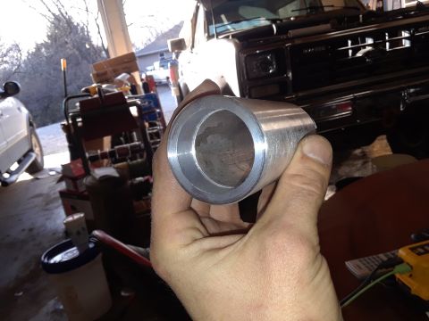 1994 Ford Bronco - Close-up of a metal pipe fitting being held, with a truck in the garage behind it.