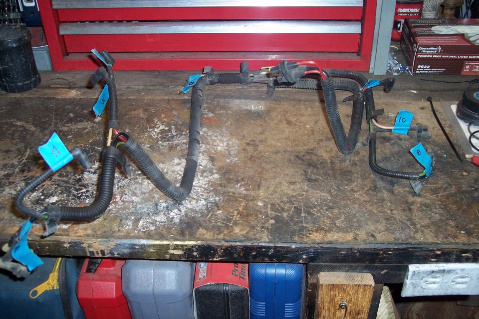 Wiring harness with blue tape labels on a workbench