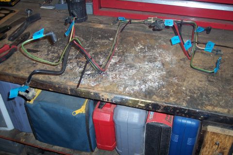 1995 Ford Bronco - Wiring harness with numbered blue tape labels sits on a workbench, likely for a Ford Bronco.
