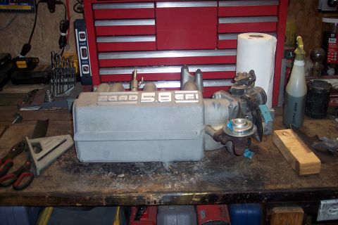 1995 Ford Bronco - A Ford 5.8 EFI intake manifold is shown on a cluttered workbench.