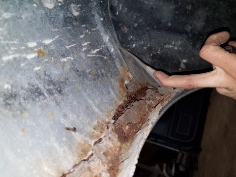1987 Ford Bronco - Severe rust damage visible on the wheel well liner of a vehicle.