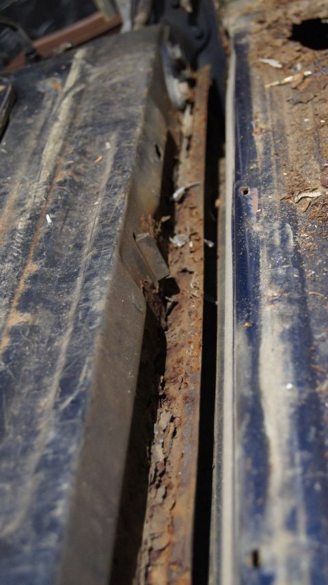 1987 Ford Bronco - This close-up view reveals extensive rust damage on the vehicle's undercarriage, indicating structural compromise.
