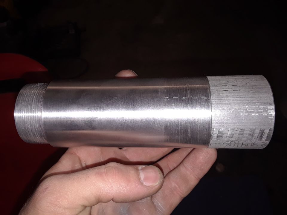 Machined aluminum part with threaded end and etched markings, held in hand