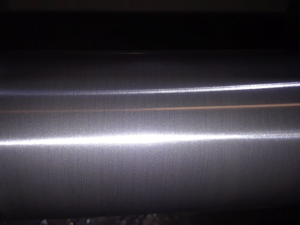 Close-up of a textured metal surface with horizontal lines and bright reflections