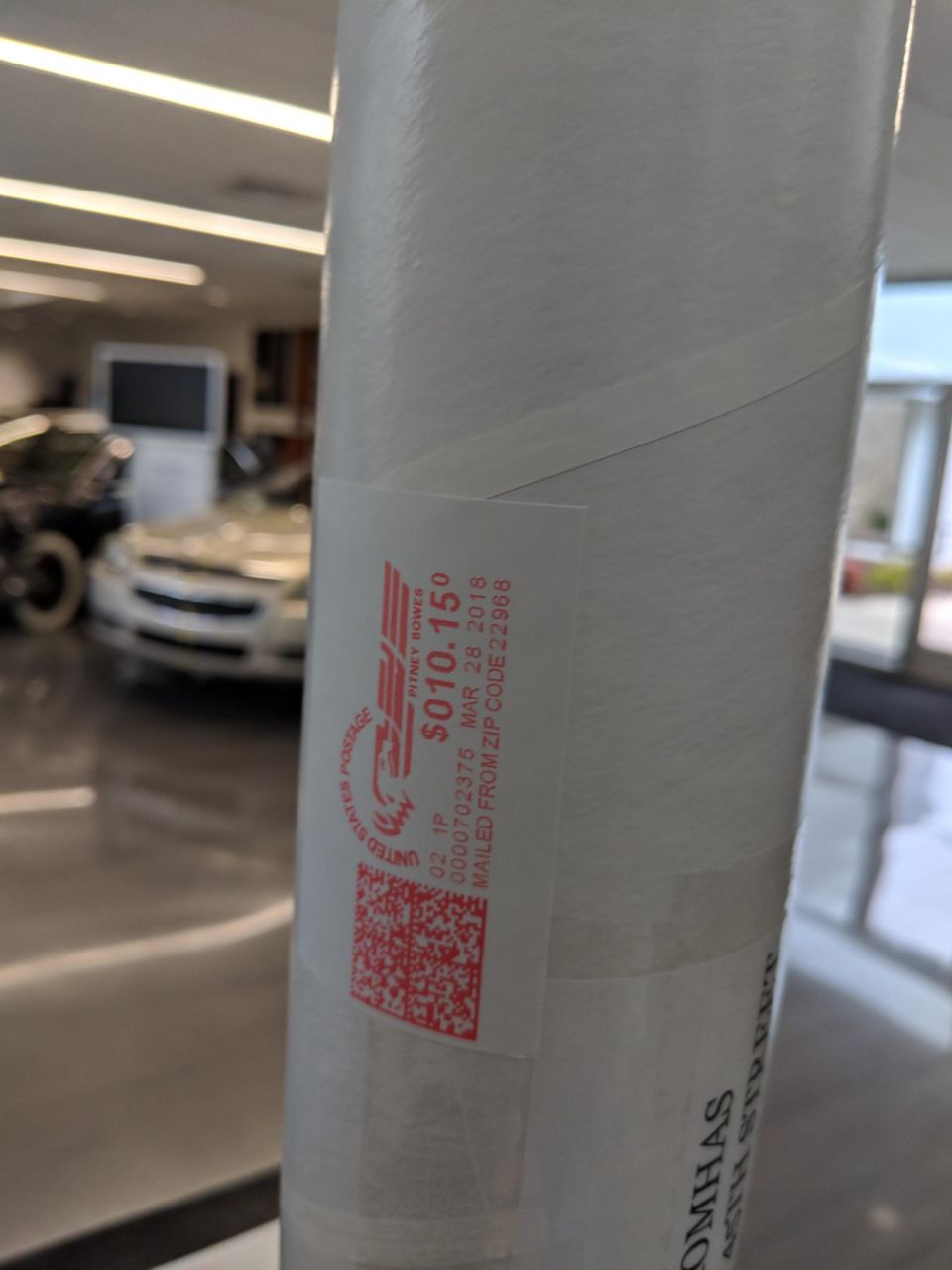 Postage label on a rolled document showing $010.150 and March 28, 2018.